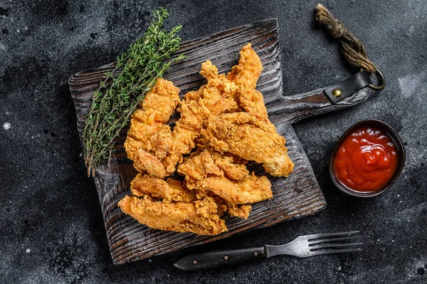 Biftek Parmaklı Kızarmış Tavuk göğsü şeritleri. Siyah arka plan. Üst görünüm.