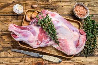 Tahta tepside çiğ keçi budu eti. Ahşap arka plan. Üst görünüm.