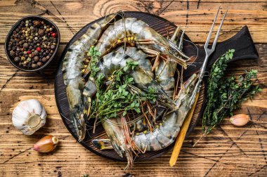 Ham siyah kaplan karidesleri kesme tahtasında otlarla birlikte. Ahşap arka plan. Üst görünüm