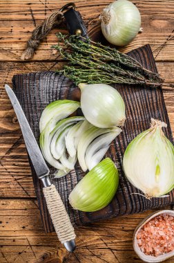 Tahta kesme tahtasında dilimlenmiş çiğ beyaz soğan. Ahşap arka plan. Üst görünüm