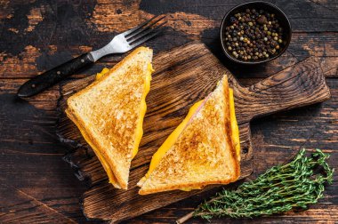 Kızarmış jambon ve erimiş peynirli sandviç. Koyu ahşap arka plan. Üst görünüm.