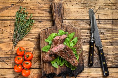 Kesme tahtasının üzerinde ızgara kesilmiş etekli et bifteği. Ahşap arka plan. Üst görünüm