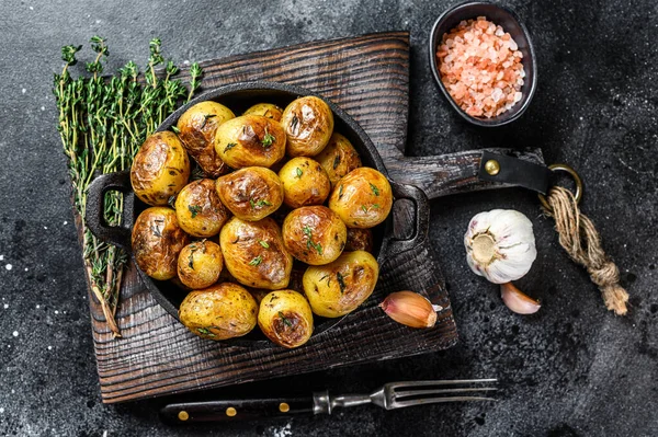 Baked youg potato with thyme in a pan Black background. Top view — Stock Photo, Image