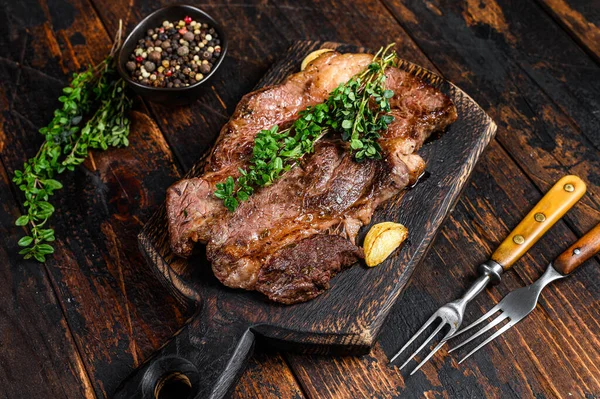 Bistecca di manzo alla griglia Chuck eye roll su un tagliere. Fondo in legno scuro. Vista dall'alto — Foto Stock