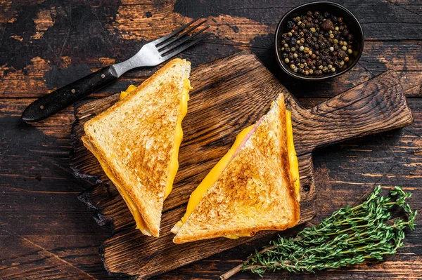 Kızarmış jambon ve erimiş peynirli sandviç. Koyu ahşap arka plan. Üst görünüm.