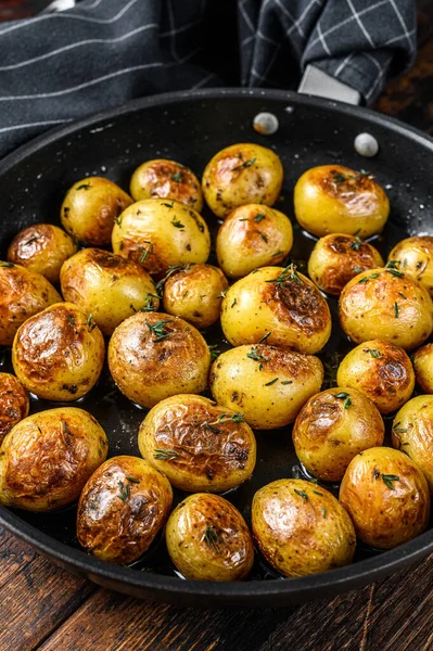 Baked baby potatoes in a cast iron skillet. Dark wooden background. Top view — Stock Photo, Image