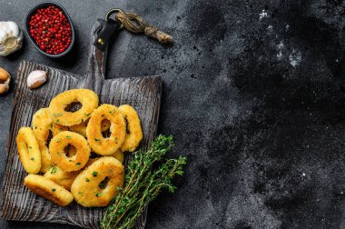 Kesme tahtasının üzerinde kızartılmış kalamar halkaları. Siyah arka plan. Üst Manzara. Boşluğu kopyala.