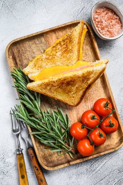 Kesme tahtasında ev yapımı kızarmış jambonlu ve peynirli sandviç. Beyaz arka plan. Üst görünüm.