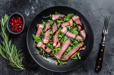 Izgara biftek salatası, roka, nar ve sebze. Siyah arka plan. Üst görünüm.