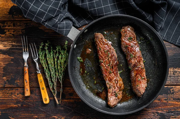 Grilovaný steak z mačety na pánvi. Tmavé dřevěné pozadí. Horní pohled — Stock fotografie