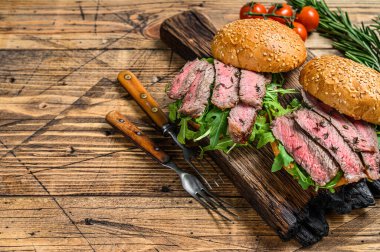 Biftek dilimli hamburger, roka ve ıspanak. Ahşap arka plan. Üst Manzara. Boşluğu kopyala.