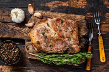 Kesme tahtasının üzerinde domuz pirzolası. Koyu ahşap arka plan. Üst görünüm