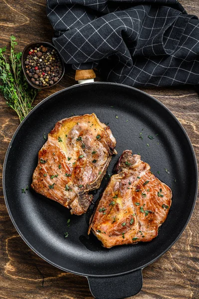 Fried pork loin steaks in a pan. Dark wooden background. Top view — Stock Photo, Image