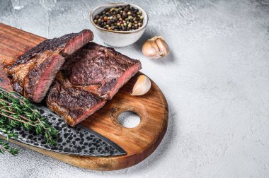 Ahşap kesme tahtasının üzerinde ızgara biftek. Beyaz arka plan. Üst Manzara. Boşluğu kopyala