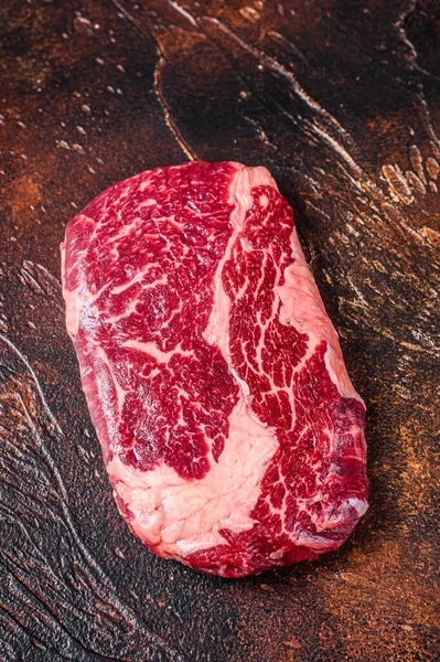 調理のために用意された肉屋のテーブルの上に生のリブアイビーフステーキ。暗い背景。トップ表示 — ストック写真