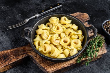 Tavada peynir soslu İtalyan tortellini makarnası. Siyah arka plan. Üst görünüm