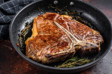 Barbekü ızgara biftek, biftek ve tabakta otlar. Karanlık arka plan. Üst görünüm