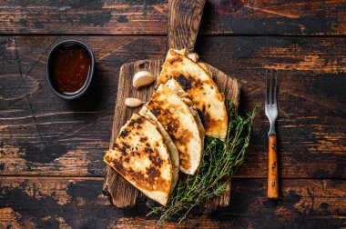 Tavuk, paprika, peynir ve kişniş soslu Meksika quesadilla 'sı. Koyu ahşap arka plan. Üst görünüm