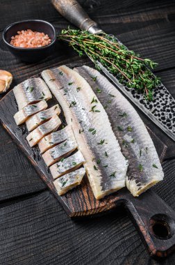 Tahta bir tahtada dilimlenmiş balık filetosu. Siyah ahşap arka plan. Üst görünüm