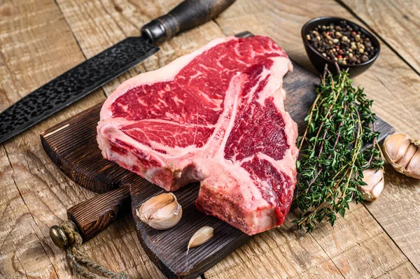 Raw Porterhouse sau T-bone carne de vită Friptură cu ierburi pe o placă de tăiere din lemn. fundal din lemn. Privire de sus — Fotografie, imagine de stoc