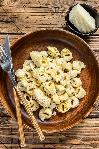 Ravioli oder Tortellini in Frischkäsesoße mit Fleisch. Holzuntergrund. Ansicht von oben — Stockfoto