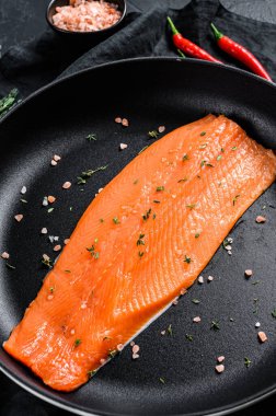 Tavada tuzlu ve biberli çiğ somon filetosu. Organik balık. Siyah arka plan. Üst görünüm