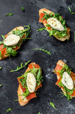 Keçi peynirli bruschetta, roka ve armut reçeli. Siyah arka plan. Üst görünüm