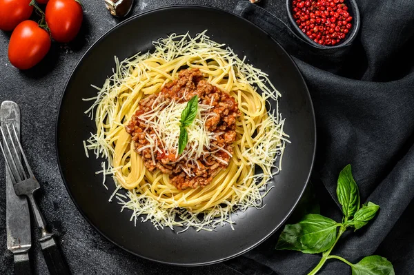Italian spaghetti pasta with tomato sauce, cheese parmesan and basil. Black background. Top view — Stock Photo, Image
