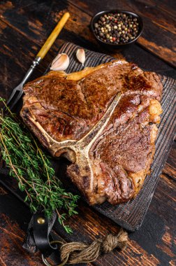 Biftek ya da ahşap bir kesme tahtasının üzerinde biftek. Koyu ahşap arka plan. Üst görünüm