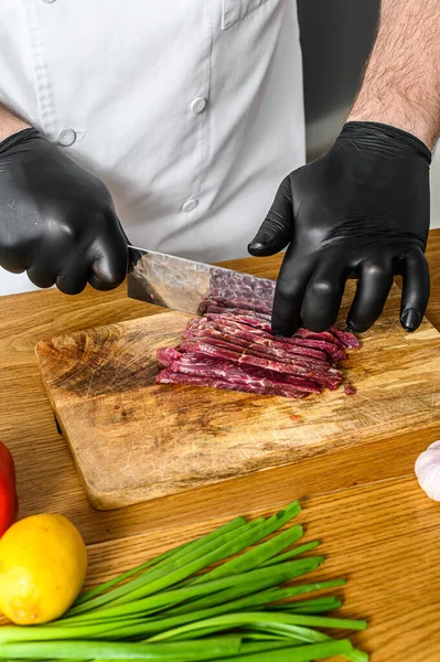 Adam çiğ et kesiyor. Siyah eldivenli bir şef. Etli tartar pişirme kavramı