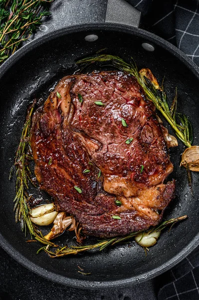 Bifteck aux côtes rôties, viande de bœuf dans une casserole. Fond noir. Vue du dessus — Photo