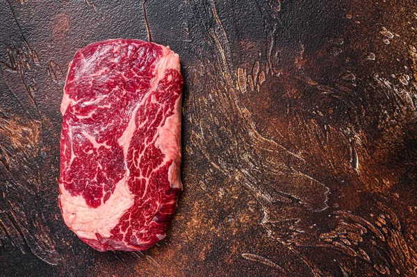Сырой стейк из говяжьего мяса на мясном столе, приготовленный для приготовления пищи. Темный фон. Вид сверху. Копирование пространства — стоковое фото