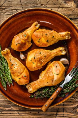 Kırsal bir tabakta taze tütsülenmiş tavuk budu ve otlar. Ahşap arka plan. Üst görünüm