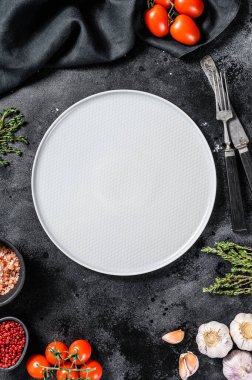 Taze çiğ sebze ve sebzelerin ortasında beyaz boş bir tabak. Sağlıklı, temiz yemek, vejetaryen, diyet yemek konsepti. Siyah arka plan. Üst Manzara. Boşluğu kopyala