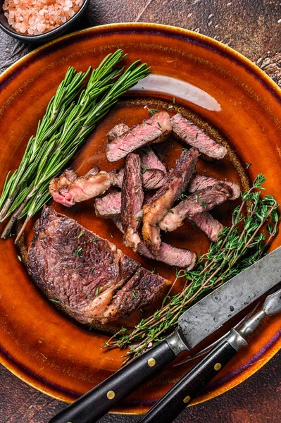 Potongan tulang rusuk panggang atau daging iga rebus steak di piring pedesaan. Latar belakang gelap. Tampilan atas — Stok Foto