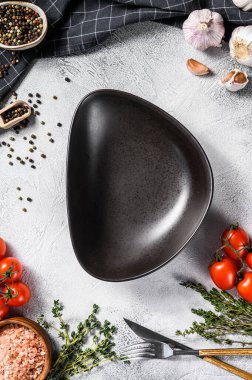 Taze çiğ sebze ve sebzelerin ortasında siyah boş bir tabak. Sağlıklı, temiz yemek, vejetaryen, diyet yemek konsepti. Beyaz arka plan. Üst Manzara. Boşluğu kopyala