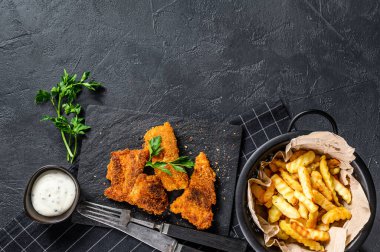Balık ve patates kızartması, geleneksel İngiliz yemekleri. Siyah arka plan. Üst Manzara. Boşluğu kopyala
