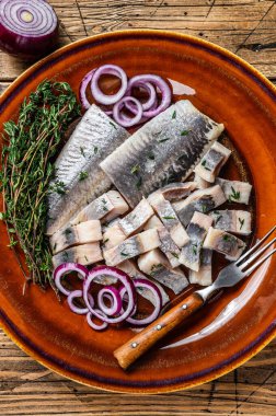 Salamura edilmiş balık salamura edilmiş fileto kekik ve soğanlı bir tabakta. Ahşap arka plan. Üst görünüm