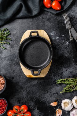 Taze çiğ sebzelerin ve sebzelerin ortasında siyah boş bir tava. Sağlıklı, temiz yemek, vejetaryen, diyet yemek konsepti. Siyah arka plan. Üst Manzara. Boşluğu kopyala