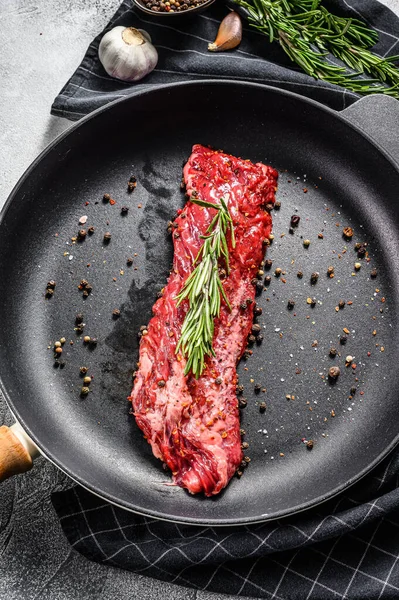 Bistecca cruda di manzo marmorizzato, filetto in padella con ingredienti per la cottura. Sfondo grigio. Vista dall'alto — Foto Stock