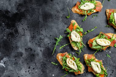 Keçi peynirli bruschetta, roka ve armut reçeli. Siyah arka plan. Üst Manzara. Boşluğu kopyala