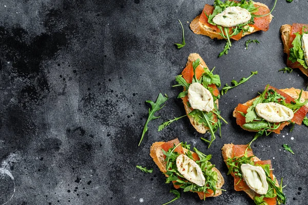 bruschetta with goat cheese, arugula and pear marmalade. Black background. Top view. Copy space