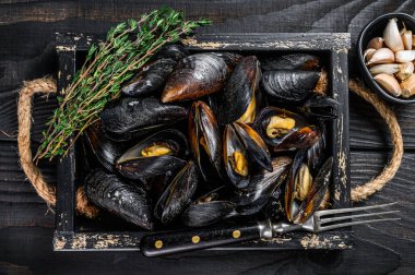 Kabuklu midyeler ahşap bir tepside otlarla birlikte. Siyah ahşap arka plan. Üst görünüm