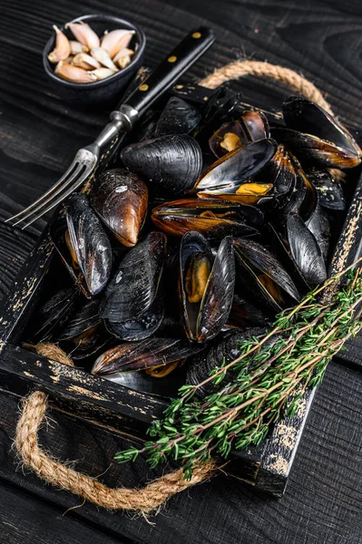 Stoom mosselen in schelpen in een houten dienblad met kruiden. Zwarte houten achtergrond. Bovenaanzicht — Stockfoto