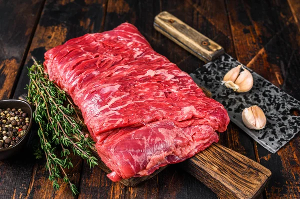 一大块生牛肉,用香草和肉片切肉.深色木制背景。顶部视图 — 图库照片