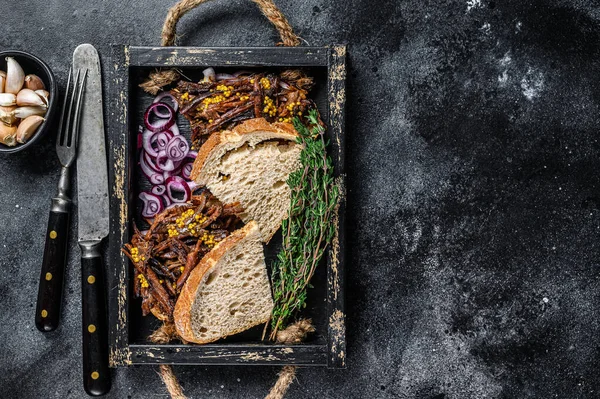 Brisket Sandwich with smoked beef meat in a wooden tray. Black background. Top view. Copy space