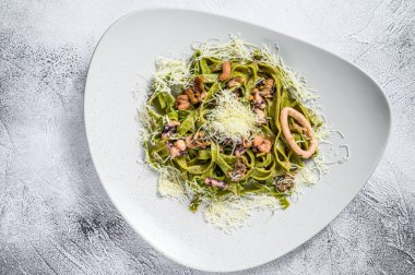 Peynirli, deniz mahsullü, karides, mürekkep balığı, ahtapot ve midyeli yeşil ıspanaklı fettucine makarna. Gri arka plan. Üst görünüm