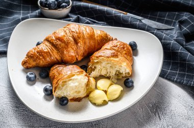 Taze kruvasan, tereyağı ve yabanmersini. Nefis bir kahvaltı. Gri arka plan. Üst görünüm