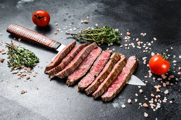 Gegrilltes und in Scheiben geschnittenes Flank rare Steak. Marmor Rindfleisch. Schwarzer Hintergrund. Ansicht von oben — Stockfoto