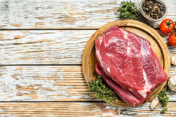 Raw Round beef cut on a wooden board. White background. Top view. Copy space — Stock Photo, Image